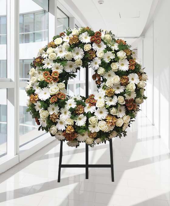 Coroa fúnebre circular de flores brancas e tons acastanhados, sobre tripé