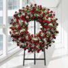Coroa fúnebre circular de rosas vermelhas com flores brancas miúdas, sobre tripé