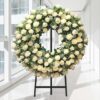 Coroa fúnebre circular de rosas brancas e creme, sobre tripé