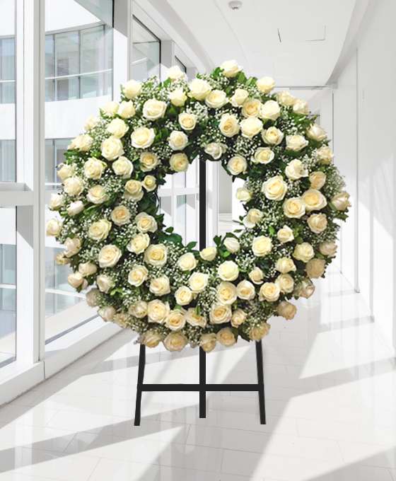 Coroa fúnebre circular de rosas brancas e creme, sobre tripé