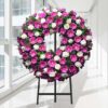 Coroa fúnebre circular de gérberas rosa e rosas brancas, sobre tripé