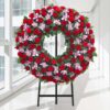 Coroa fúnebre circular de rosas vermelhas e orquídeas cor-de-rosa, sobre tripé