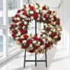 Coroa fúnebre circular de rosas vermelhas e brancas, sobre tripé