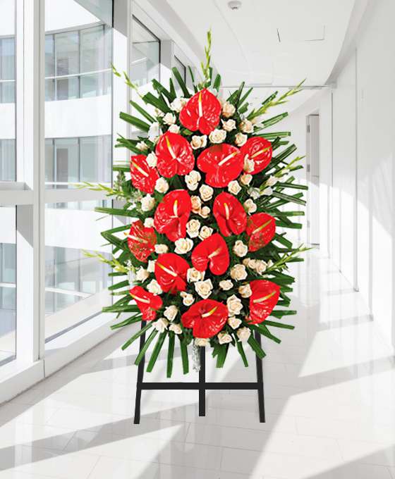Palma fúnebre vertical de antúrios vermelhos e rosas brancas, sobre tripé